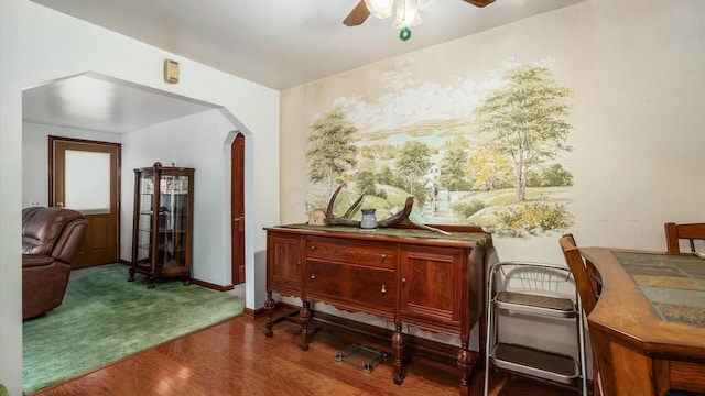 living area featuring arched walkways, dark wood-style flooring, a ceiling fan, and baseboards