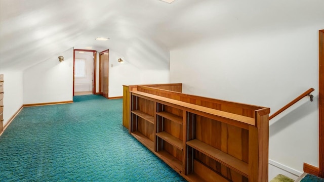 additional living space with lofted ceiling, dark carpet, and baseboards