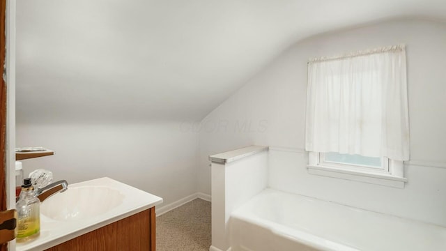 bathroom featuring lofted ceiling, a bath, and vanity