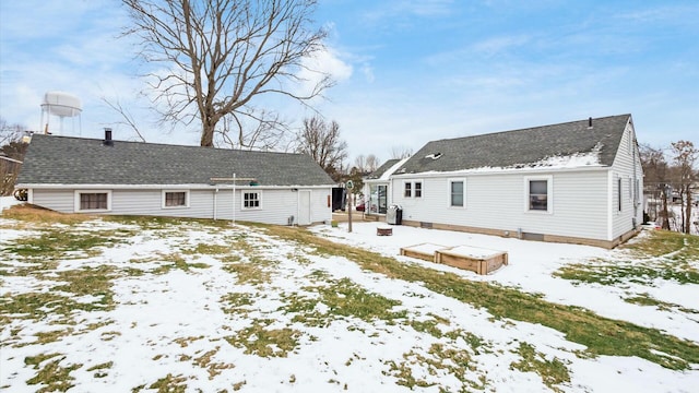 snow covered property with roof with shingles