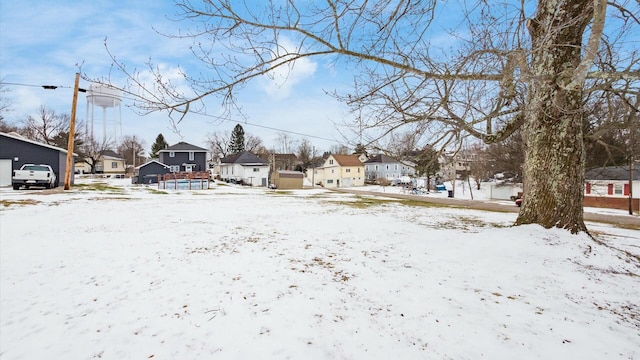 yard covered in snow featuring a garage and a residential view