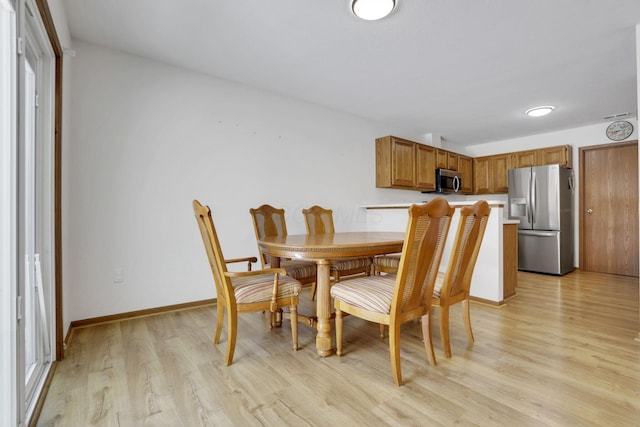 dining area featuring light wood-style flooring and baseboards