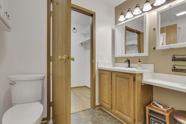 bathroom with toilet, vanity, and baseboards