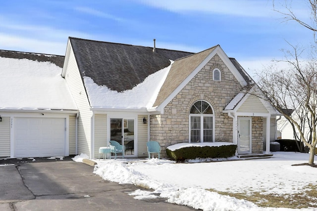 view of front facade featuring driveway, a shingled roof, and an attached garage