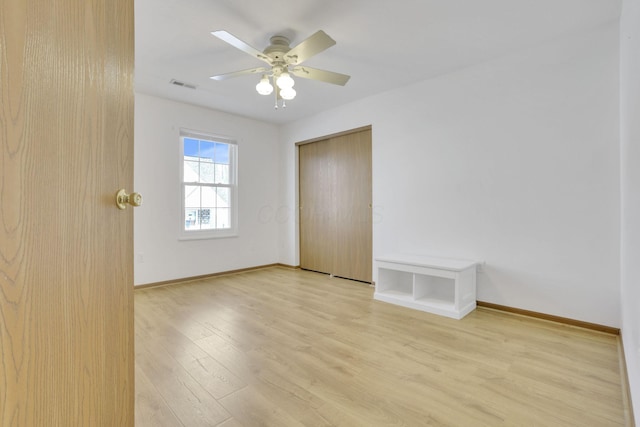 spare room featuring visible vents, a ceiling fan, light wood-style flooring, and baseboards