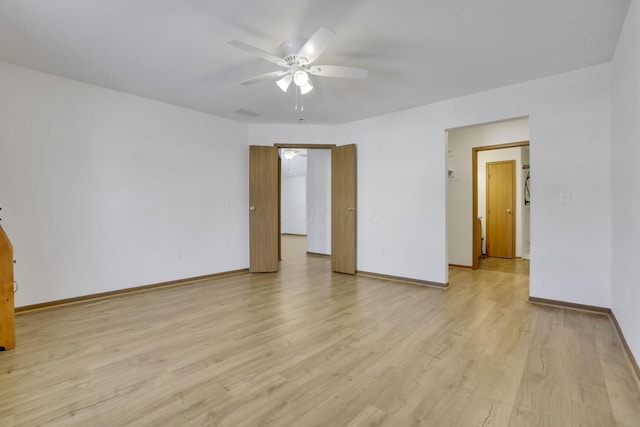 empty room featuring baseboards, ceiling fan, and light wood-style floors