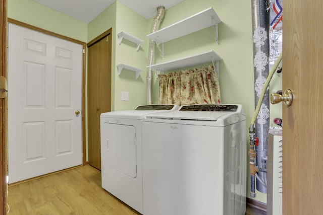 laundry area with laundry area, washing machine and dryer, and light wood finished floors