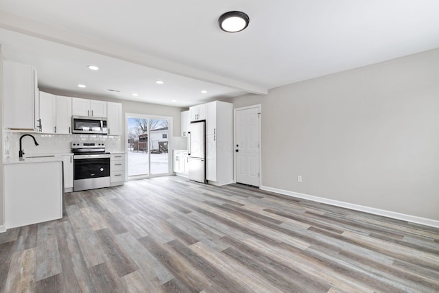 kitchen featuring white cabinets, decorative backsplash, stainless steel appliances, light countertops, and a sink