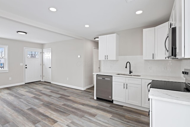 kitchen with stainless steel appliances, white cabinetry, a sink, and baseboards