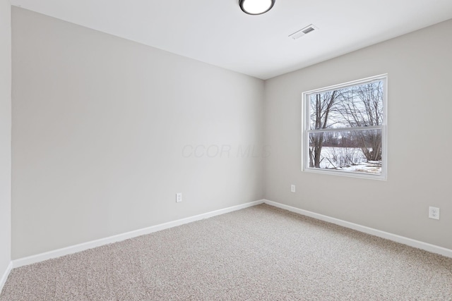 carpeted spare room featuring visible vents and baseboards