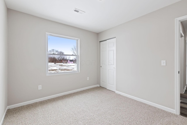 unfurnished bedroom with carpet floors, baseboards, visible vents, and a closet