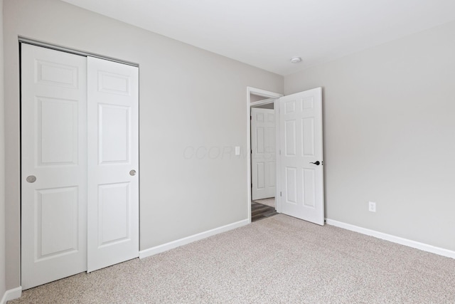 unfurnished bedroom featuring carpet, baseboards, and a closet