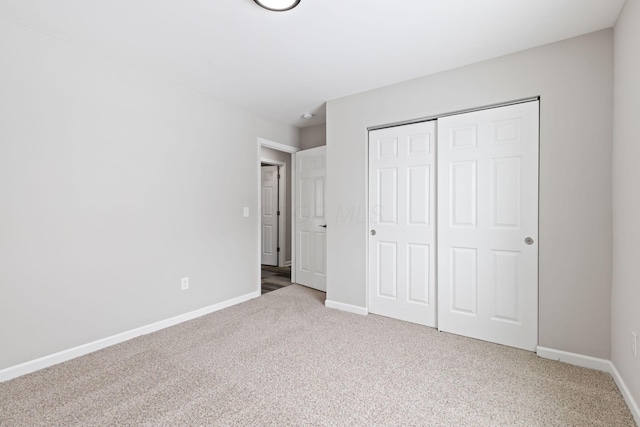 unfurnished bedroom with a closet, carpet flooring, and baseboards