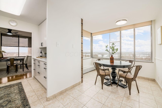 dining area with a ceiling fan, baseboards, and light tile patterned floors