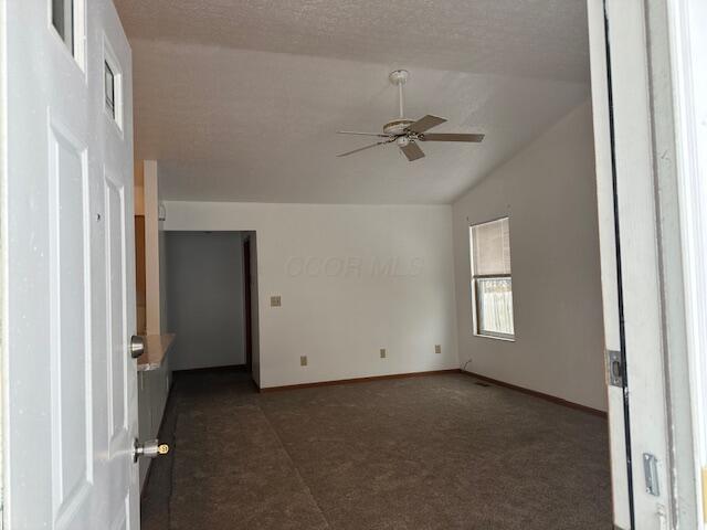 empty room featuring lofted ceiling, ceiling fan, a textured ceiling, and baseboards