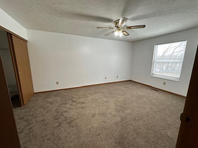 unfurnished room featuring carpet floors, a textured ceiling, baseboards, and a ceiling fan