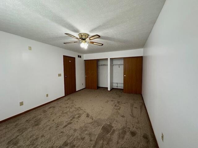 unfurnished bedroom featuring a textured ceiling, carpet, two closets, and visible vents