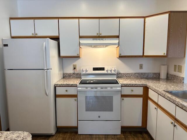 kitchen with white appliances, white cabinetry, and under cabinet range hood