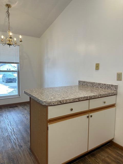 kitchen with vaulted ceiling, light countertops, dark wood finished floors, and white cabinetry