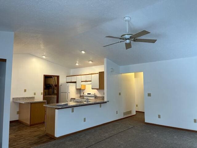 kitchen with brown cabinetry, freestanding refrigerator, a ceiling fan, vaulted ceiling, and a peninsula