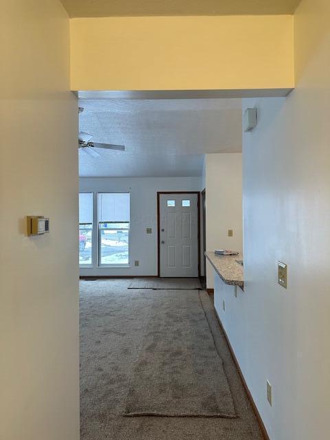 entrance foyer with ceiling fan, carpet flooring, and baseboards