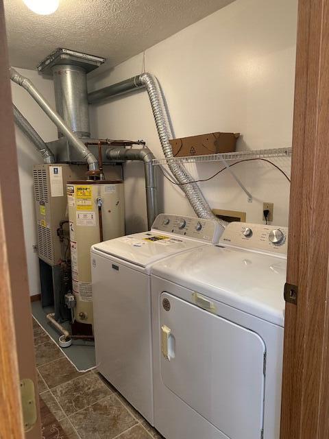 laundry room with laundry area, water heater, a textured ceiling, and washing machine and clothes dryer