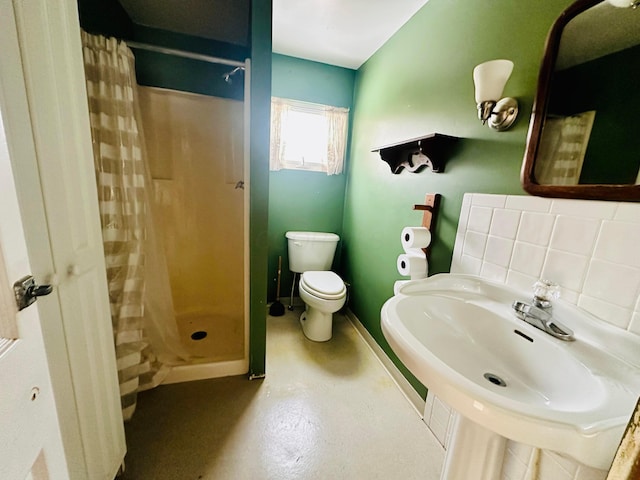 bathroom featuring toilet, baseboards, finished concrete flooring, backsplash, and a stall shower