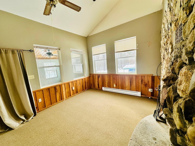 empty room with a baseboard radiator, wainscoting, wood walls, and light carpet