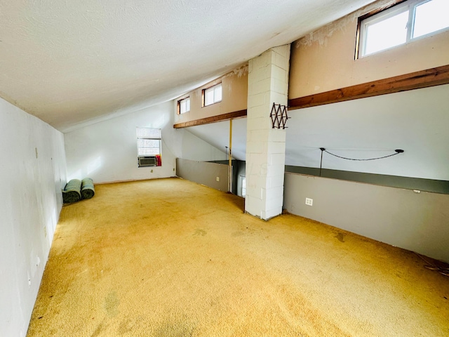 additional living space featuring cooling unit, lofted ceiling, carpet flooring, and a textured ceiling