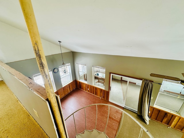 staircase with vaulted ceiling and wood walls