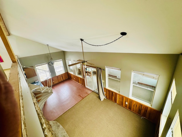 additional living space featuring light carpet, ceiling fan, wooden walls, and vaulted ceiling