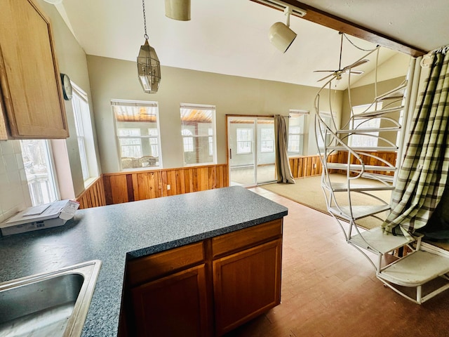 kitchen featuring lofted ceiling, wood finished floors, a sink, a ceiling fan, and dark countertops