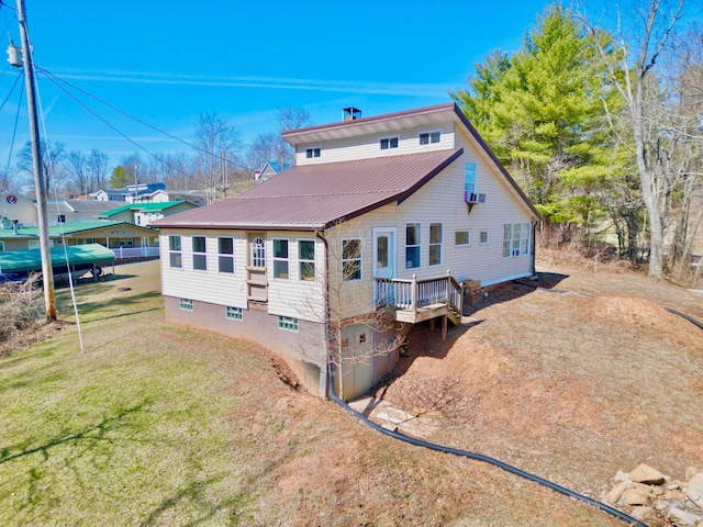 back of house featuring a deck, a lawn, and metal roof