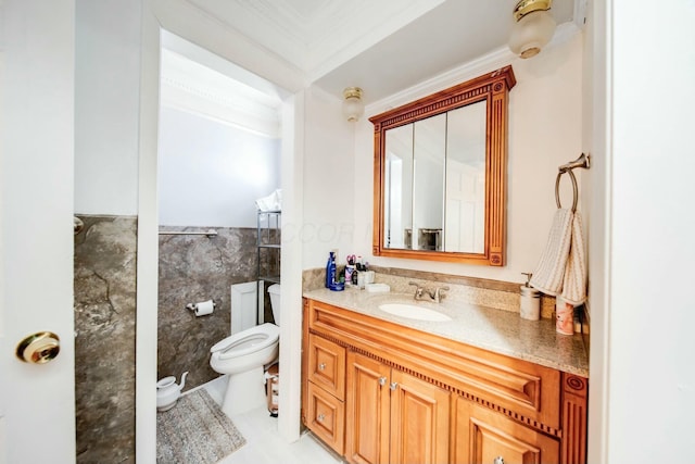 bathroom with toilet, a wainscoted wall, vanity, tile walls, and ornamental molding