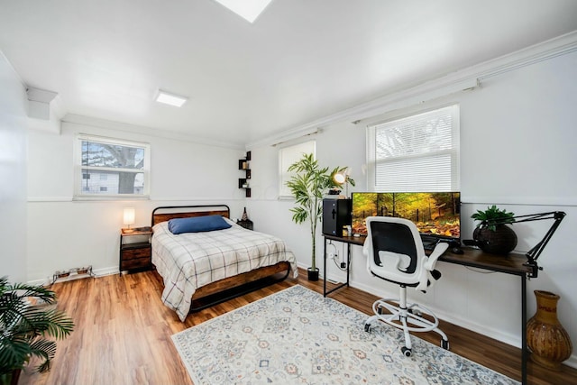 bedroom with ornamental molding, wood finished floors, and baseboards