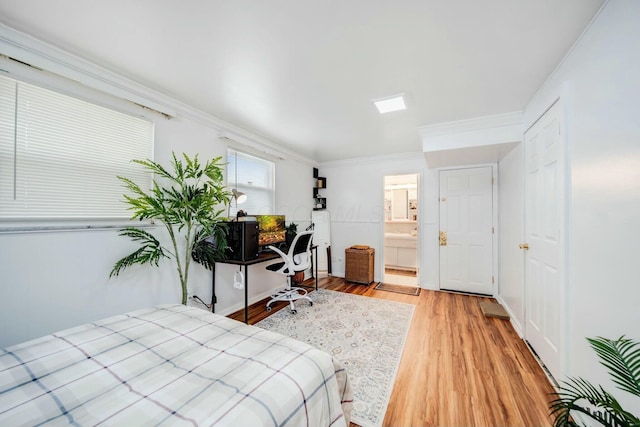 bedroom featuring crown molding, ensuite bath, baseboards, and wood finished floors