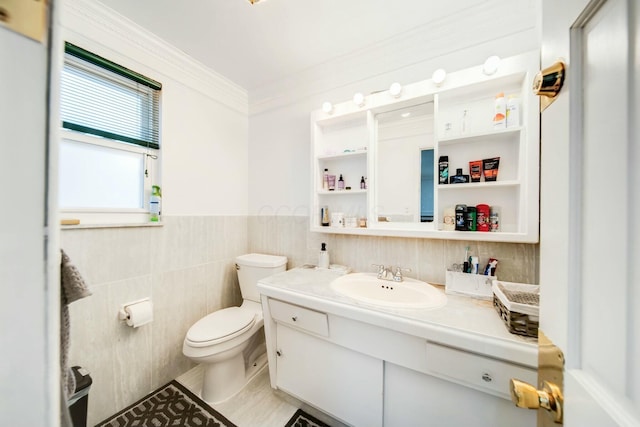 half bathroom with toilet, vanity, tile walls, ornamental molding, and wainscoting