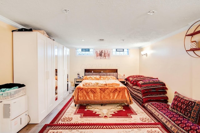 bedroom featuring a textured ceiling, ornamental molding, and light wood-type flooring