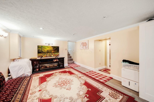 living room featuring ornamental molding, wood finished floors, a textured ceiling, and stairs