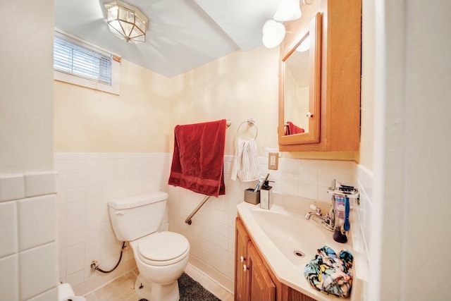 half bathroom featuring toilet, wainscoting, tile walls, and vanity