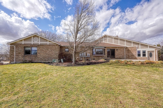 back of property featuring a yard and brick siding