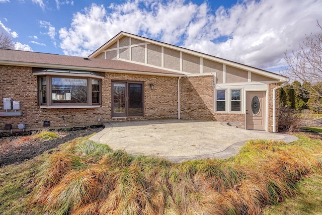 back of house featuring brick siding and a patio