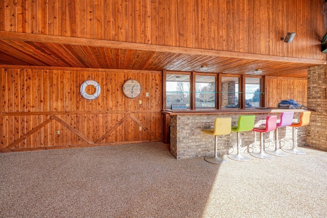 bar featuring a bar, carpet, wooden walls, and wood ceiling