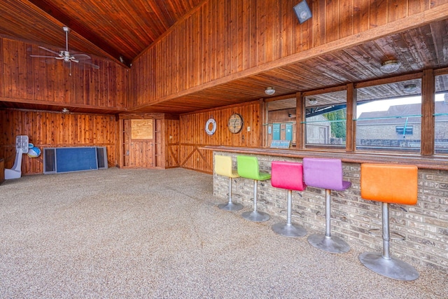 interior space featuring a dry bar, carpet flooring, wood walls, high vaulted ceiling, and wooden ceiling