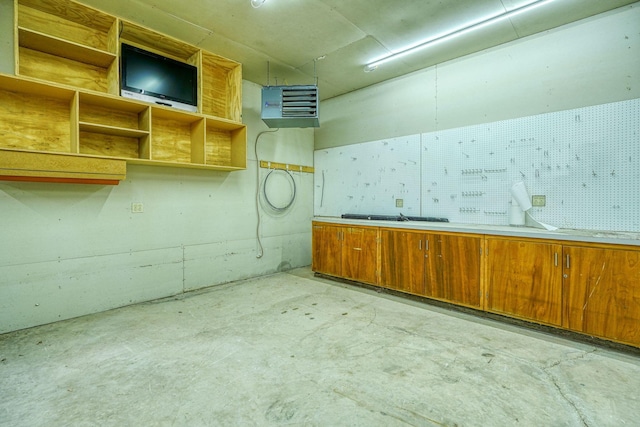 interior space featuring brown cabinetry, unfinished concrete floors, and open shelves