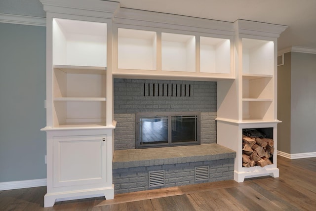 unfurnished living room with a brick fireplace, visible vents, baseboards, and wood finished floors