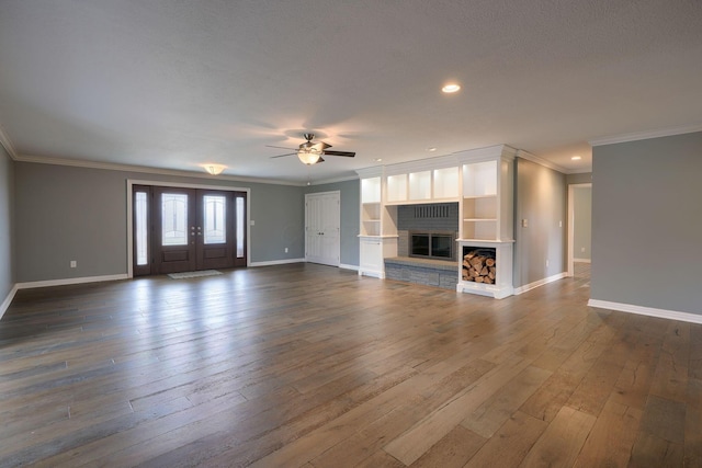 unfurnished living room featuring dark wood-style floors, a brick fireplace, baseboards, and crown molding