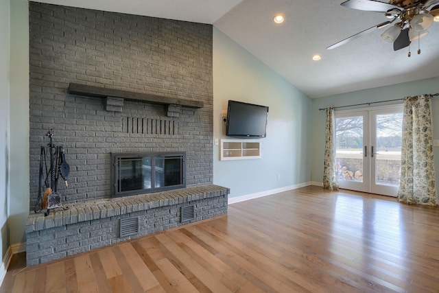 unfurnished living room with french doors, a fireplace, ceiling fan, vaulted ceiling, and wood finished floors