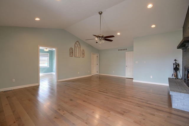 unfurnished living room with a brick fireplace, visible vents, and wood finished floors