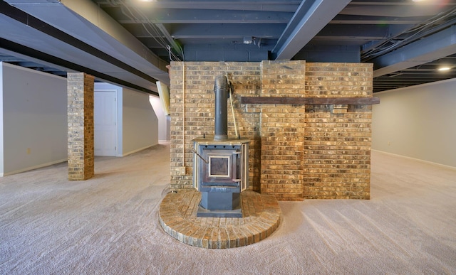 finished basement with a wood stove, carpet flooring, and baseboards